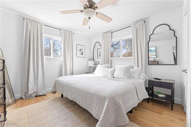 bedroom with a ceiling fan, wood finished floors, and baseboards