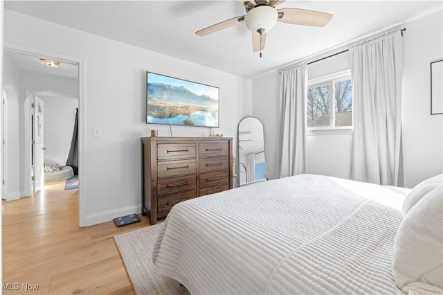 bedroom featuring baseboards, light wood finished floors, and ceiling fan