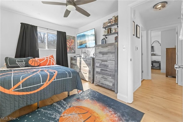 bedroom featuring baseboards, light wood-style floors, and a ceiling fan