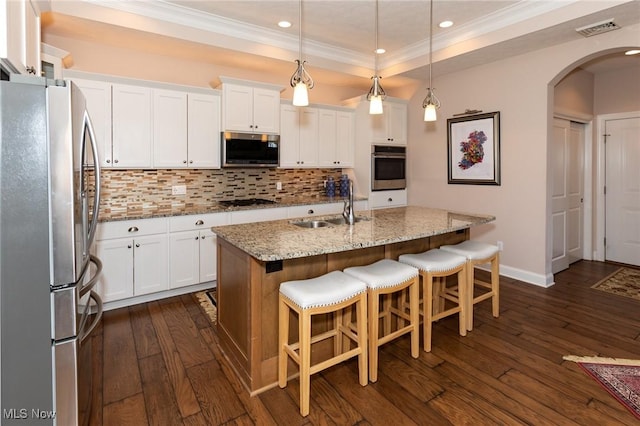 kitchen featuring visible vents, arched walkways, a sink, ornamental molding, and stainless steel appliances