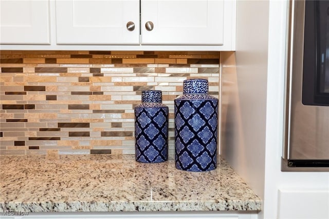 details featuring white cabinetry and light stone countertops