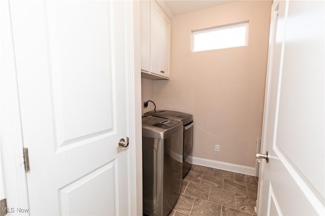 clothes washing area with washer and dryer, cabinet space, baseboards, and stone finish flooring