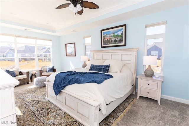 bedroom featuring baseboards, light carpet, a raised ceiling, and ceiling fan