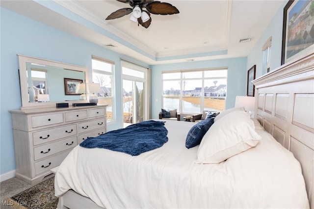 carpeted bedroom with a tray ceiling, multiple windows, and visible vents