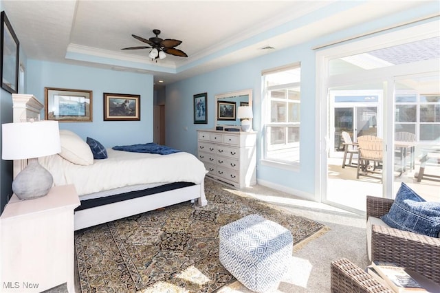 bedroom featuring baseboards, carpet, a tray ceiling, ornamental molding, and a ceiling fan