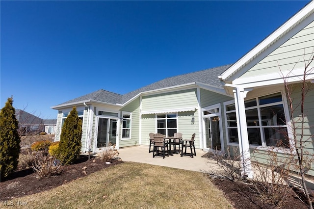 back of property with a patio and roof with shingles