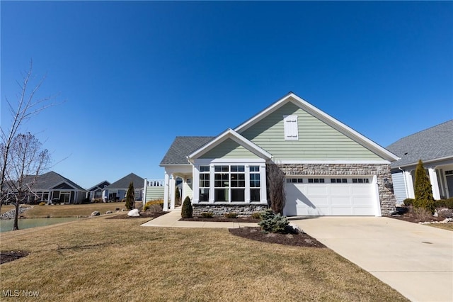 view of front of property featuring stone siding, an attached garage, concrete driveway, and a front yard