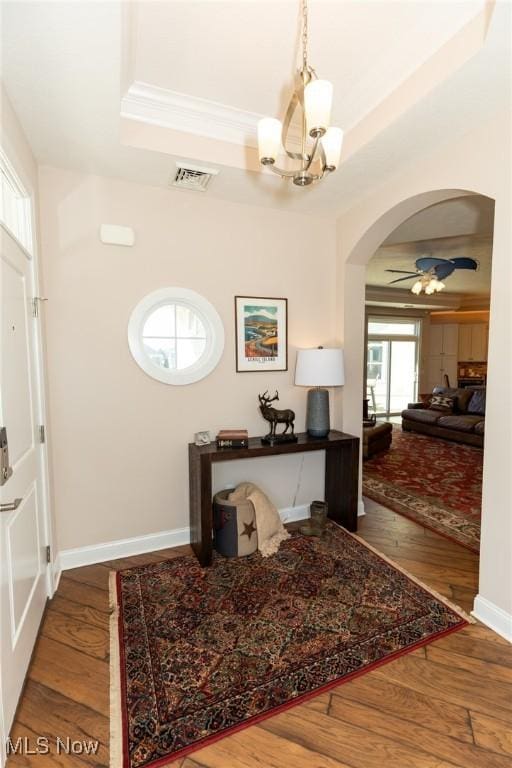 office space with a tray ceiling, baseboards, visible vents, and wood finished floors