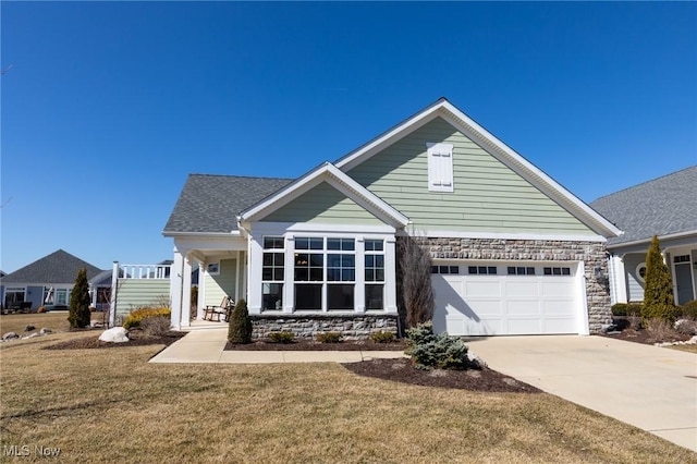 view of front of home featuring a front yard, stone siding, driveway, and a shingled roof