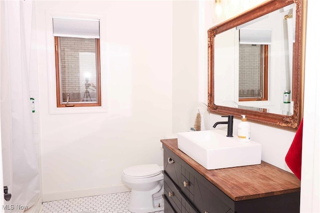 bathroom featuring vanity, toilet, baseboards, and tile patterned flooring