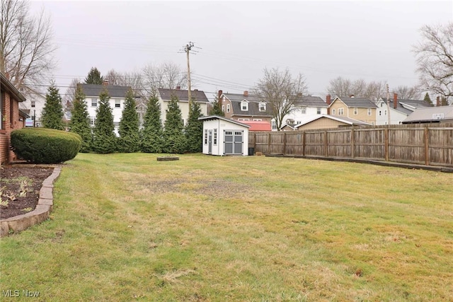 view of yard with a storage shed, a fenced backyard, and an outdoor structure