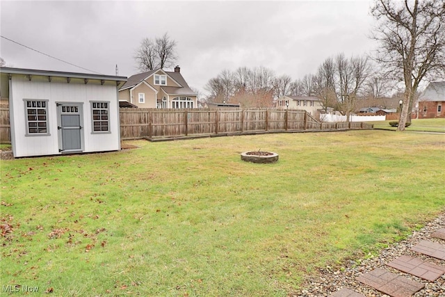 view of yard featuring a fire pit, an outdoor structure, a storage shed, and a fenced backyard