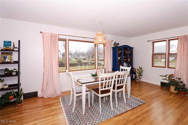 dining area featuring baseboards, plenty of natural light, and light wood finished floors