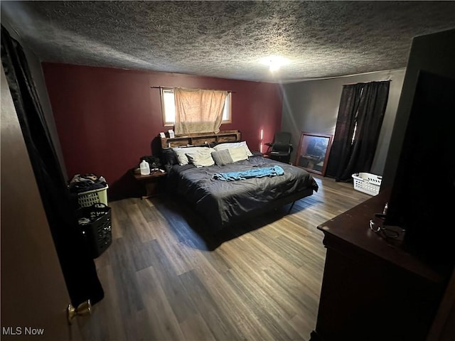 bedroom with a textured ceiling and wood finished floors