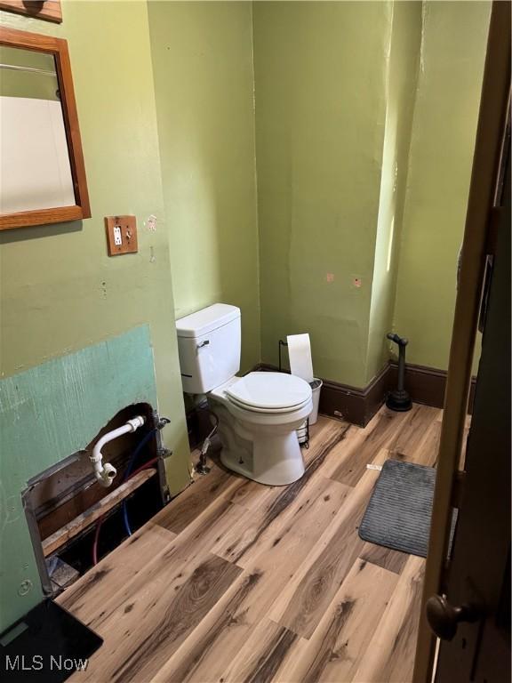 bathroom with baseboards, toilet, and wood finished floors