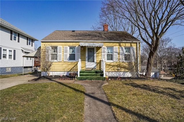 bungalow-style home with a front yard, roof with shingles, and a chimney