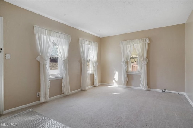 empty room with carpet flooring, baseboards, and a wealth of natural light