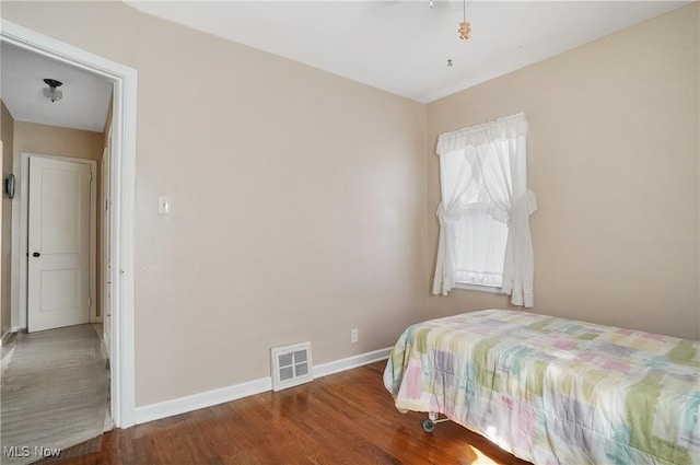 bedroom with visible vents, baseboards, and wood finished floors