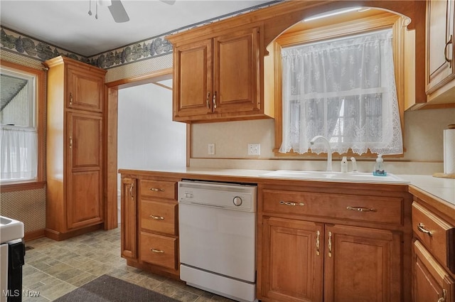 kitchen featuring brown cabinets, dishwasher, light countertops, and a sink