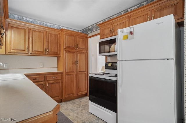 kitchen with freestanding refrigerator, a sink, light countertops, electric stove, and stainless steel microwave