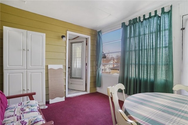 carpeted bedroom featuring wood walls