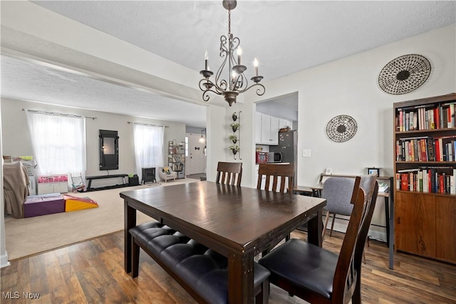 dining area with a textured ceiling, wood finished floors, and a chandelier