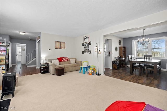 carpeted living area featuring an inviting chandelier, stairway, baseboards, and a textured ceiling