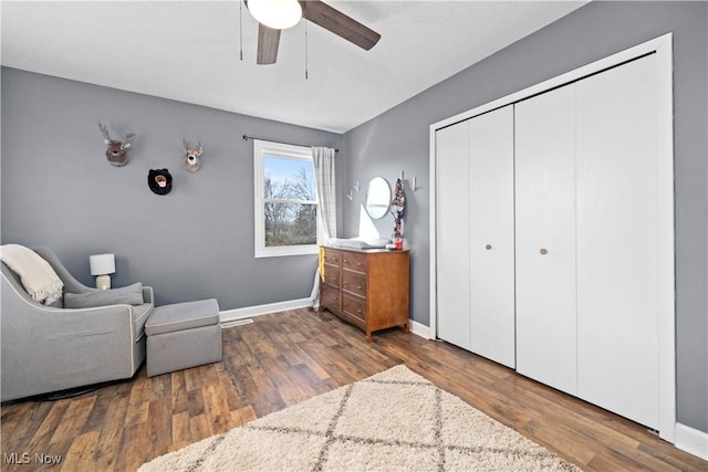 sitting room featuring a ceiling fan, baseboards, and wood finished floors