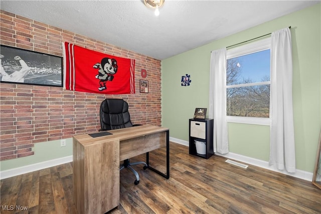 office featuring wood finished floors, baseboards, brick wall, and a textured ceiling