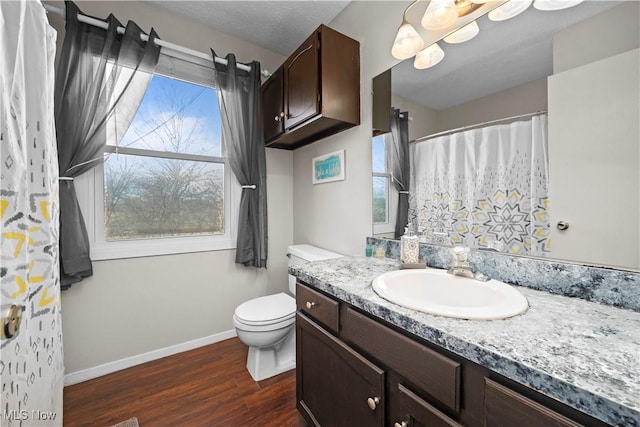 bathroom with baseboards, toilet, a shower with shower curtain, wood finished floors, and vanity