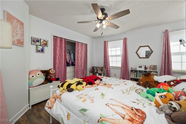 bedroom with dark wood-type flooring, multiple windows, a closet, and a textured ceiling