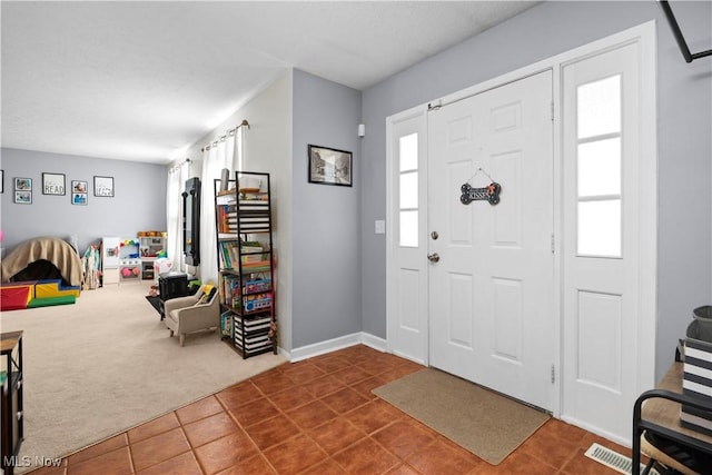 tiled foyer entrance featuring baseboards, visible vents, and carpet floors