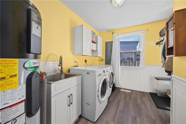 clothes washing area with heat pump water heater, cabinet space, a sink, dark wood-type flooring, and wainscoting