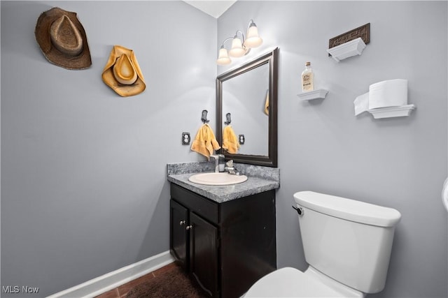 half bath featuring toilet, vanity, and baseboards