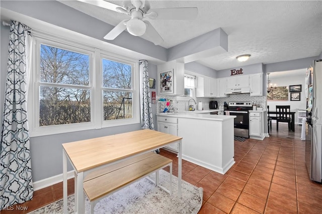 kitchen with tile patterned flooring, electric stove, white cabinetry, and backsplash