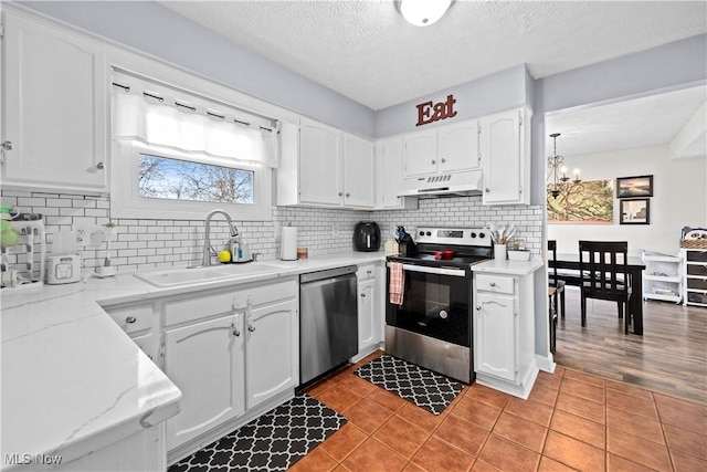 kitchen featuring under cabinet range hood, a sink, white cabinetry, appliances with stainless steel finishes, and light tile patterned flooring