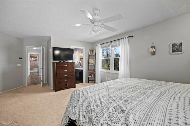 bedroom featuring a textured ceiling, ceiling fan, connected bathroom, and light carpet