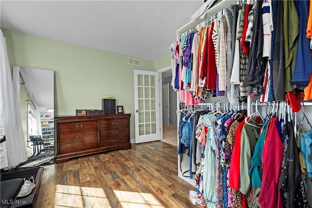 walk in closet with visible vents, wood finished floors, and french doors