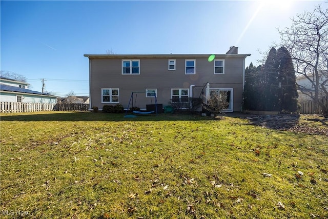 back of property featuring fence, a lawn, and a chimney