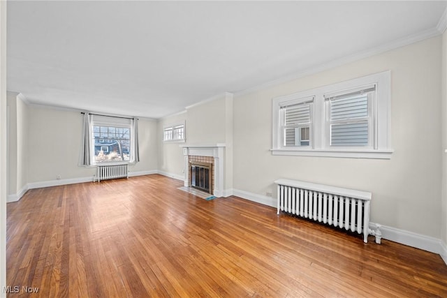 unfurnished living room featuring a fireplace with flush hearth, radiator, and wood finished floors