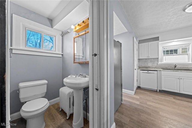 bathroom featuring tasteful backsplash, plenty of natural light, toilet, and wood finished floors