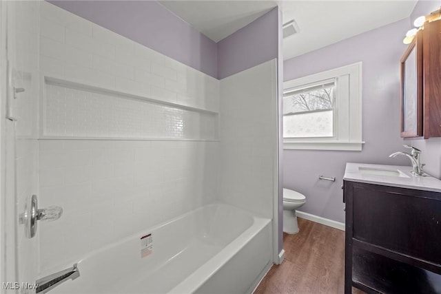 bathroom featuring baseboards, toilet, shower / bathing tub combination, wood finished floors, and vanity