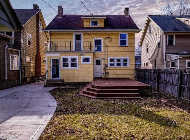 back of house with a deck, entry steps, fence, a balcony, and a chimney