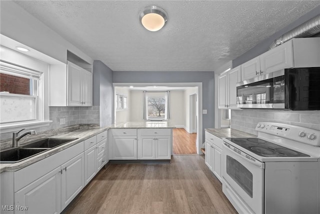 kitchen featuring stainless steel microwave, wood finished floors, white cabinetry, white electric range, and a sink