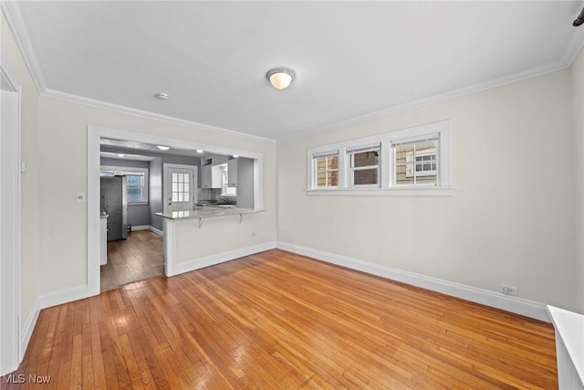 unfurnished living room featuring crown molding, light wood-style floors, and baseboards