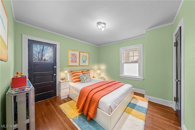 bedroom with crown molding, wood finished floors, and baseboards