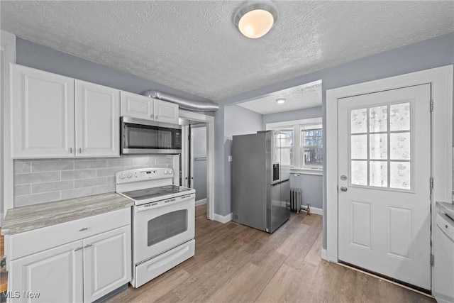 kitchen with light wood-style flooring, stainless steel appliances, light countertops, white cabinetry, and tasteful backsplash