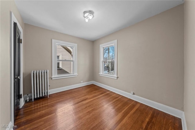 unfurnished room featuring baseboards, radiator, and wood finished floors