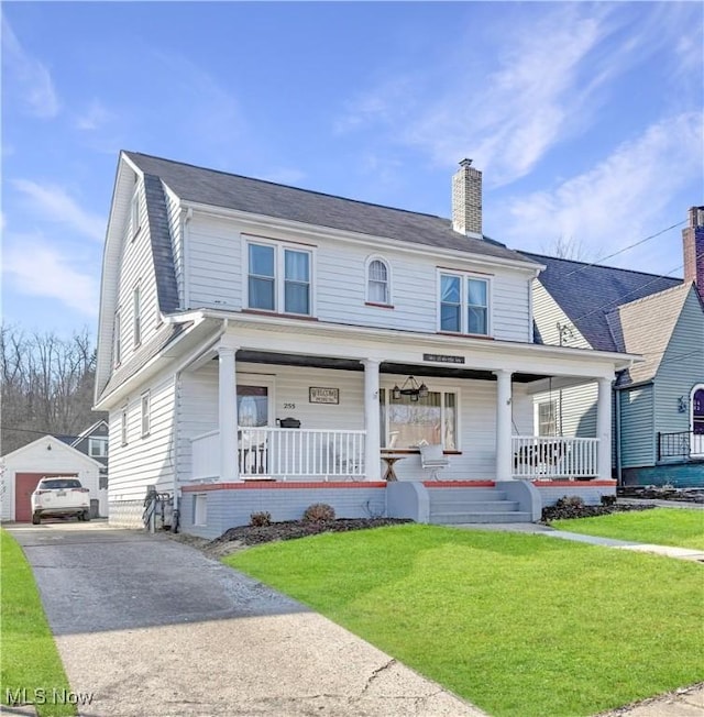 view of front of home with a front lawn, aphalt driveway, a porch, a chimney, and an outdoor structure