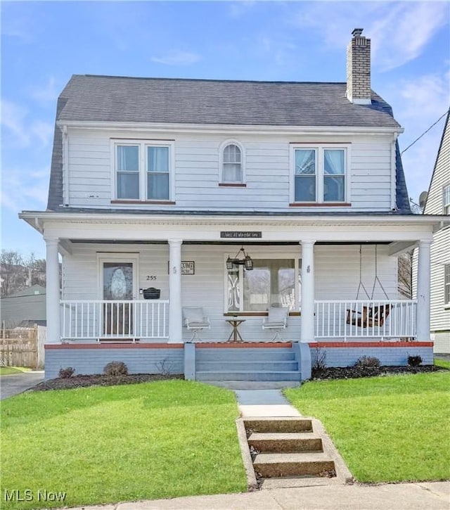 view of front of house featuring a porch, a chimney, and a front yard